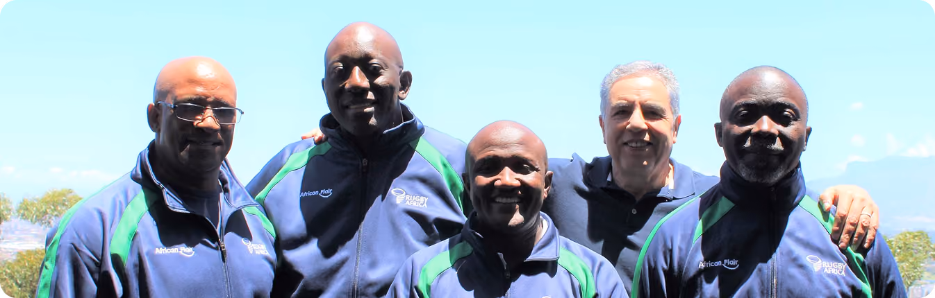 Five men standing close outdoors, four in Rugby Africa jackets and one in a dark polo shirt.