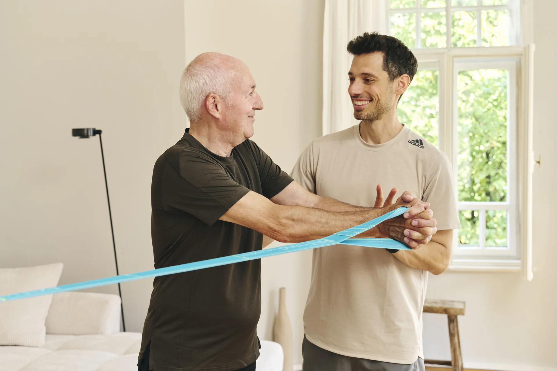 Personal Trainer Lars Traxel zeigt einem Kunden eine Übung mit einem blauen FLEXVIT-Widerstandsband beim Personal Training in München.