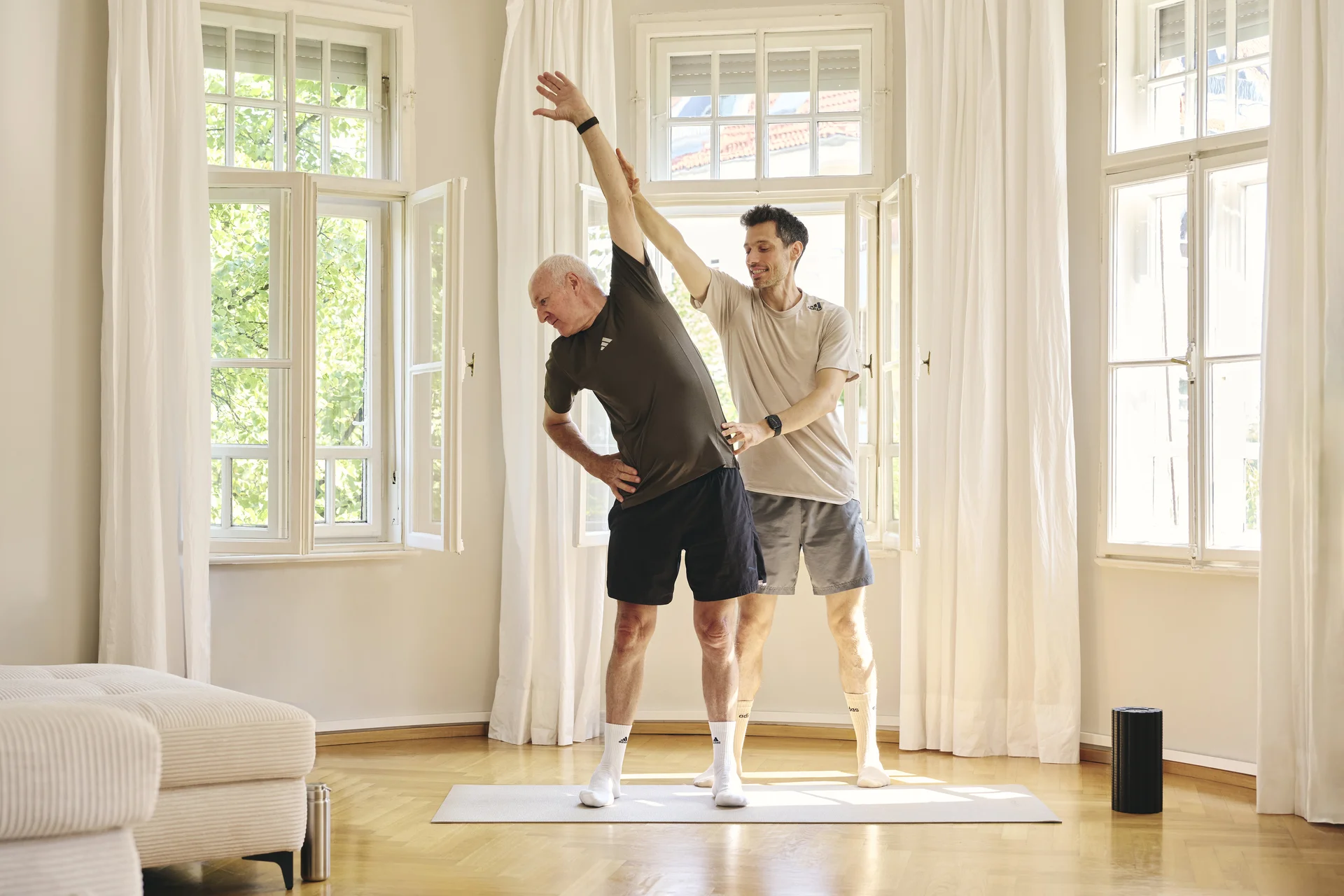 Lars Traxel begleitet einen männlichen Klienten beim individuellen Rückentraining in seiner Wohnung in München.