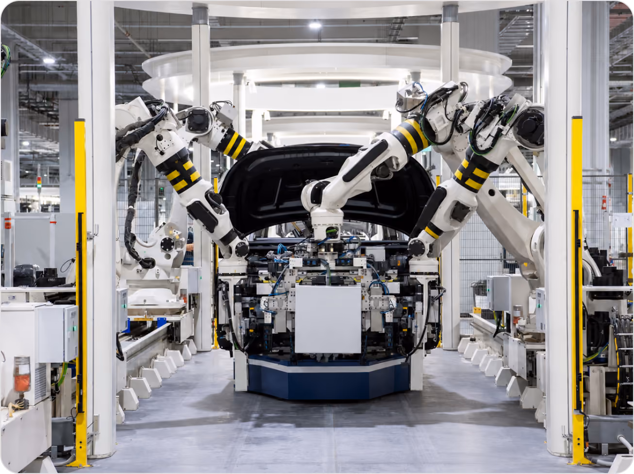 Robotic arms assembling a car with open hood in a modern automotive factory.