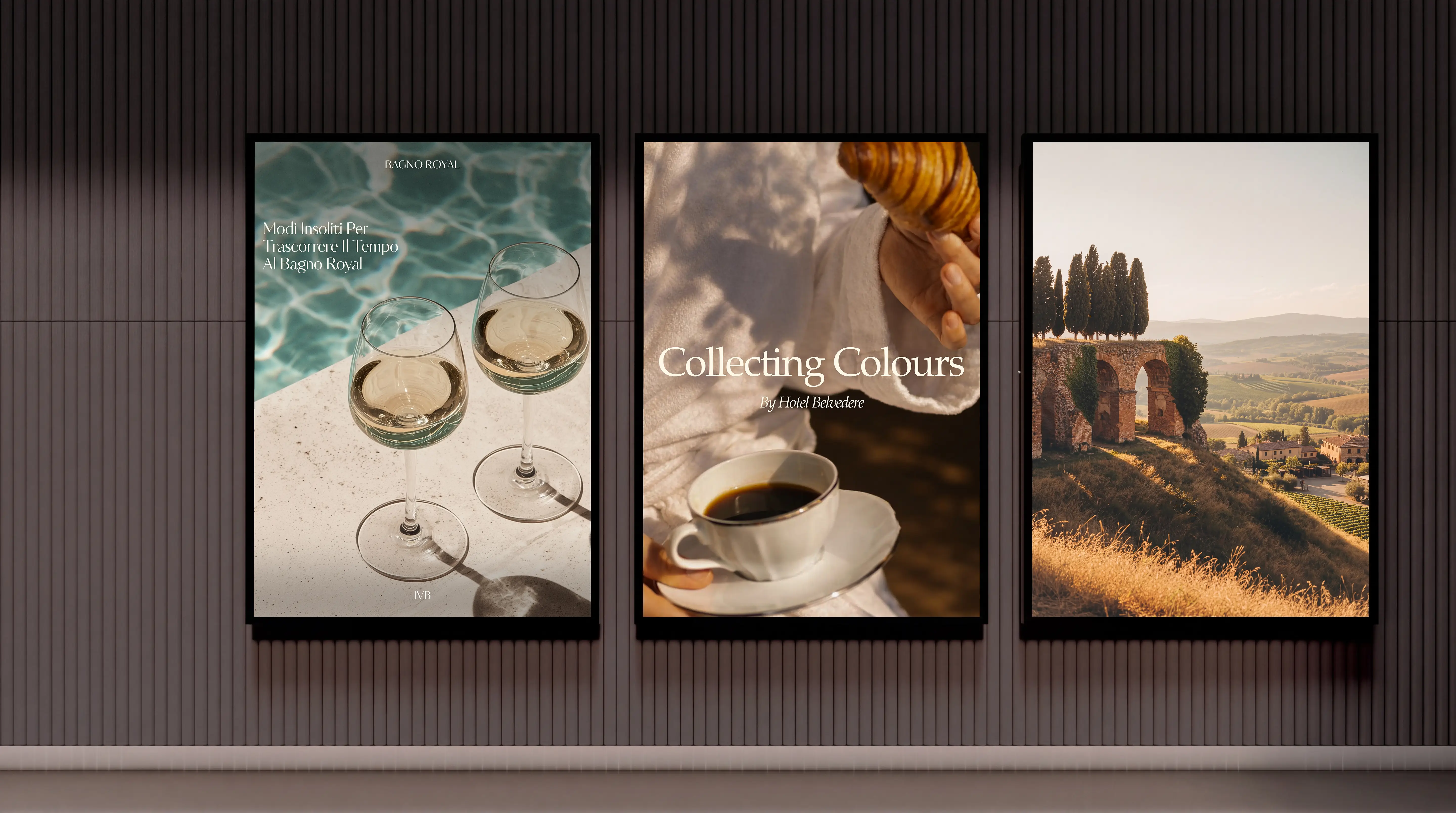 Three framed posters on a vertical wood-paneled wall: left shows two wine glasses on a poolside edge with text 'Bagno Royal Modi Insoliti Per Trascorrere Il Tempo Al Bagno Royal'; center shows a person in a white robe holding a croissant and a cup of black coffee with text 'Collecting Colours By Hotel Belvedere'; right shows a scenic landscape with ancient stone arches, tall cypress trees, and rolling hills at sunset.