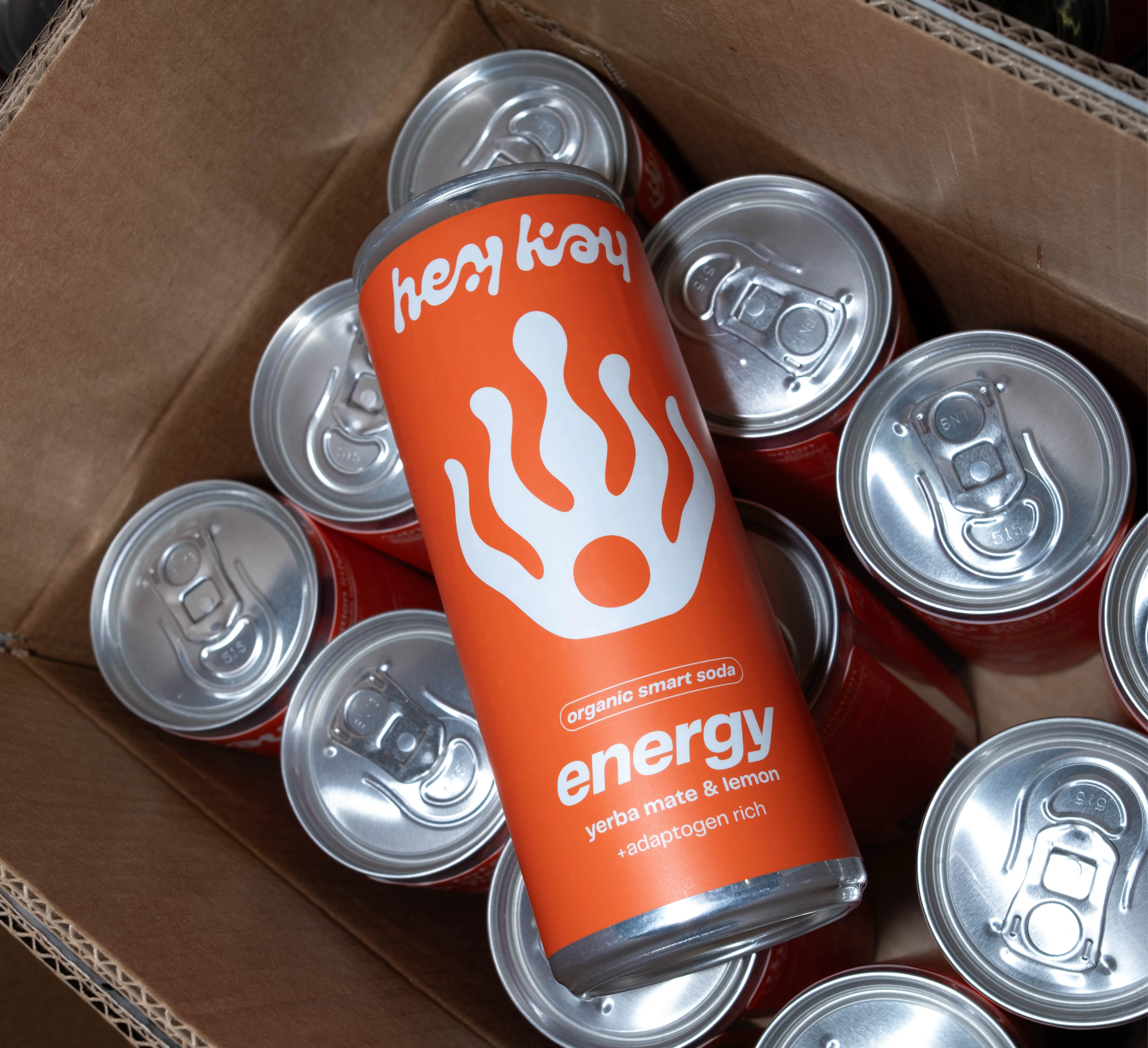 Lata de hey kay energy numa caixa de cartão com outras latas