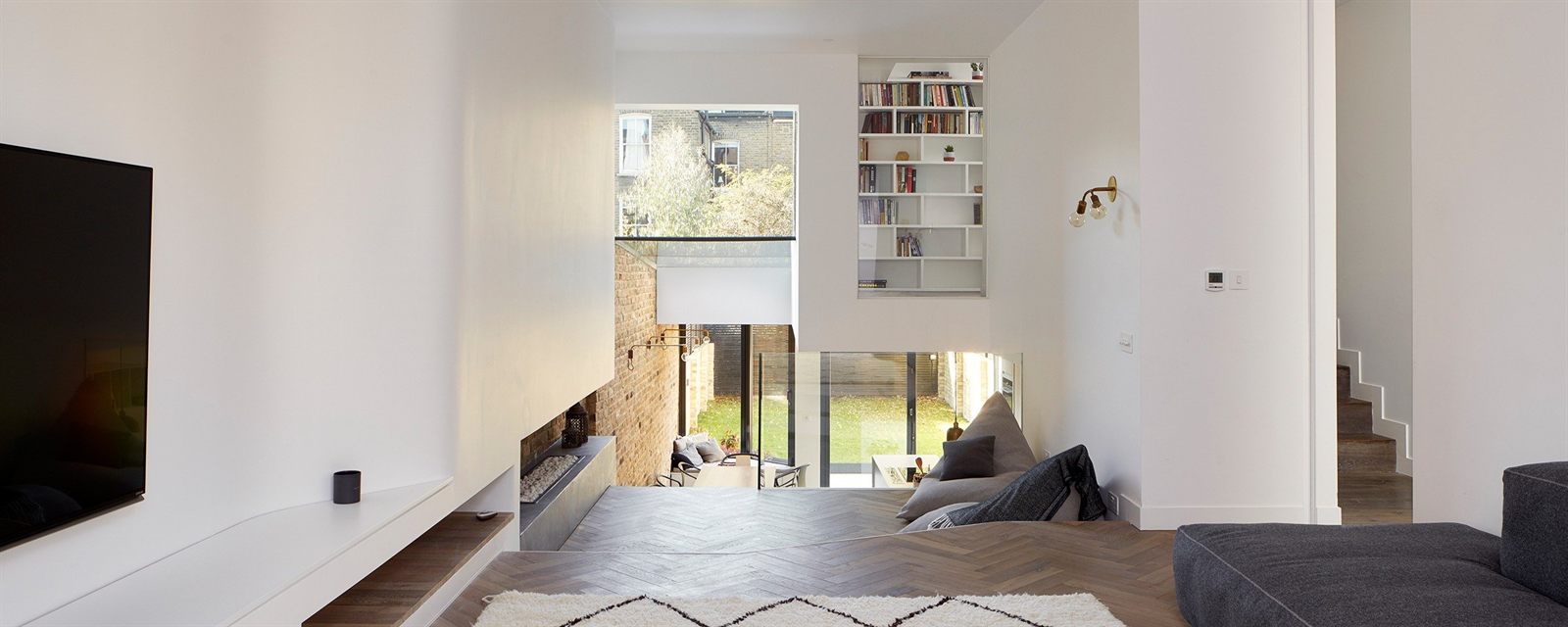 Open-plan living space stepping down to a garden through full-height glazing