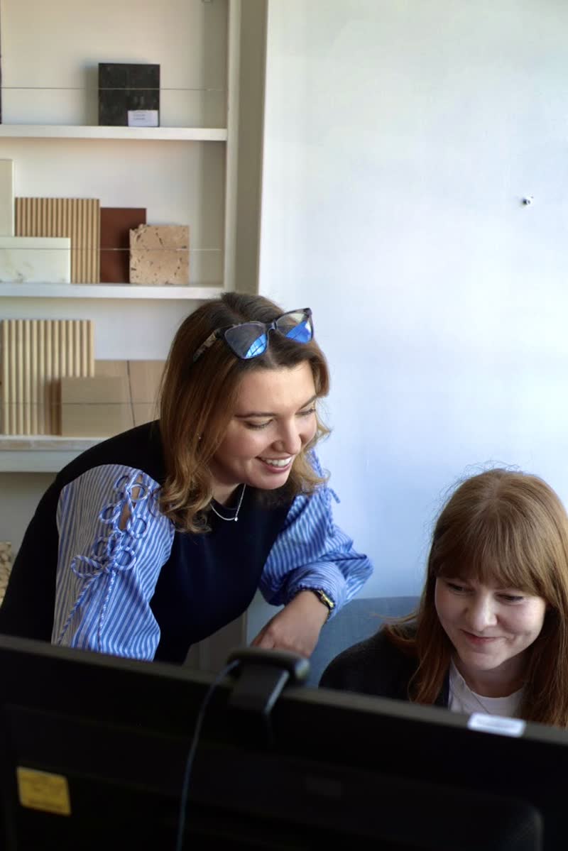 Two colleagues looking over a screen together in front of shelves of material samples.