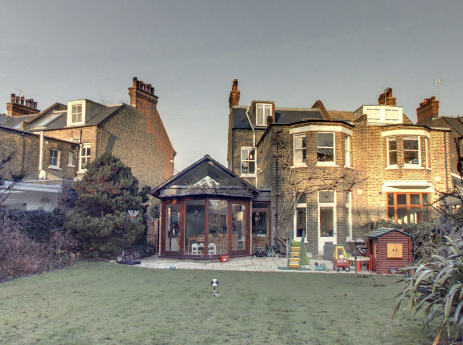 The rear of the house before the work, with a dark timber conservatory against the Victorian brickwork