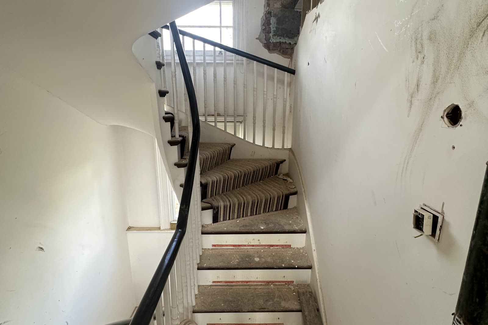 The original curved stair during the works, its black handrail in place and the wall scarred back