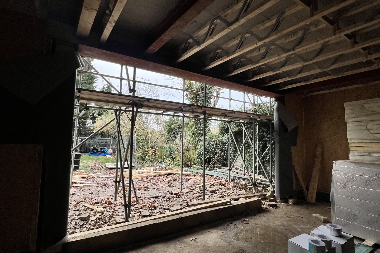 The ground floor opening to the garden during the works, joists overhead and scaffolding beyond