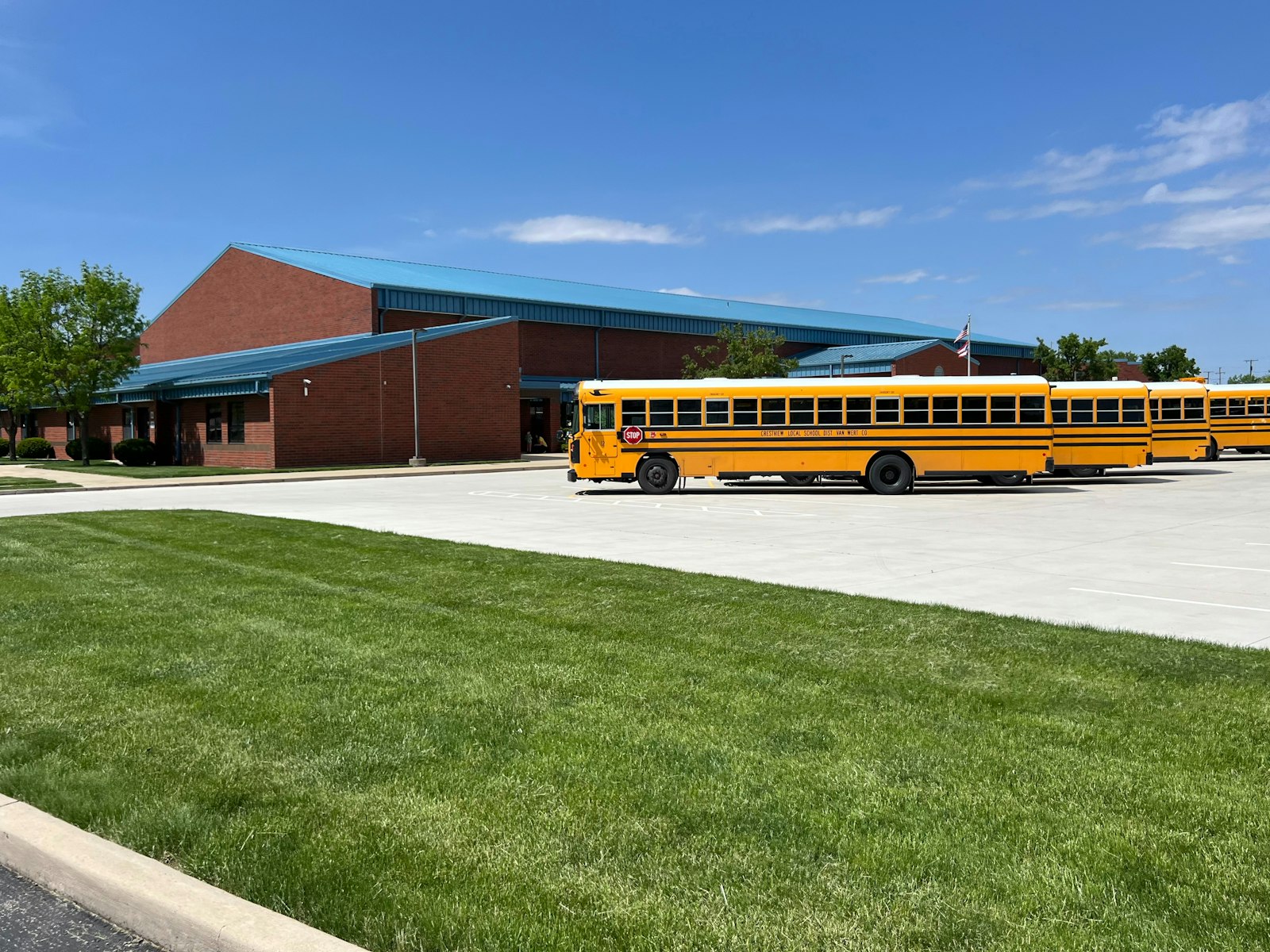 Yellow school bus parked in front of a school building | Westside Construction Group