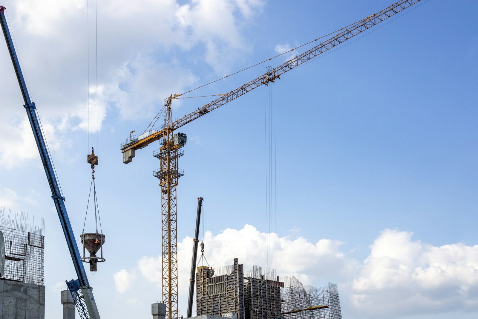 Construction cranes against a bright blue sky