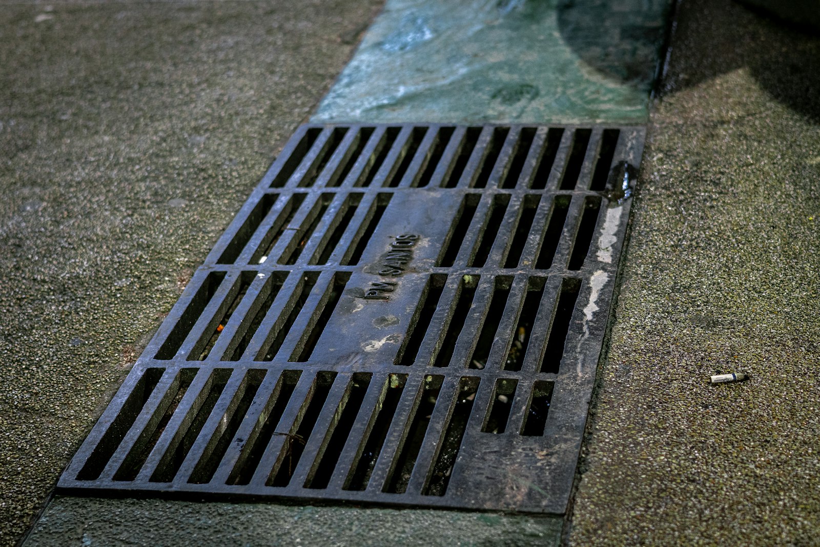 A metal stormwater drainage grate set in a concrete surface | Westside Construction Group