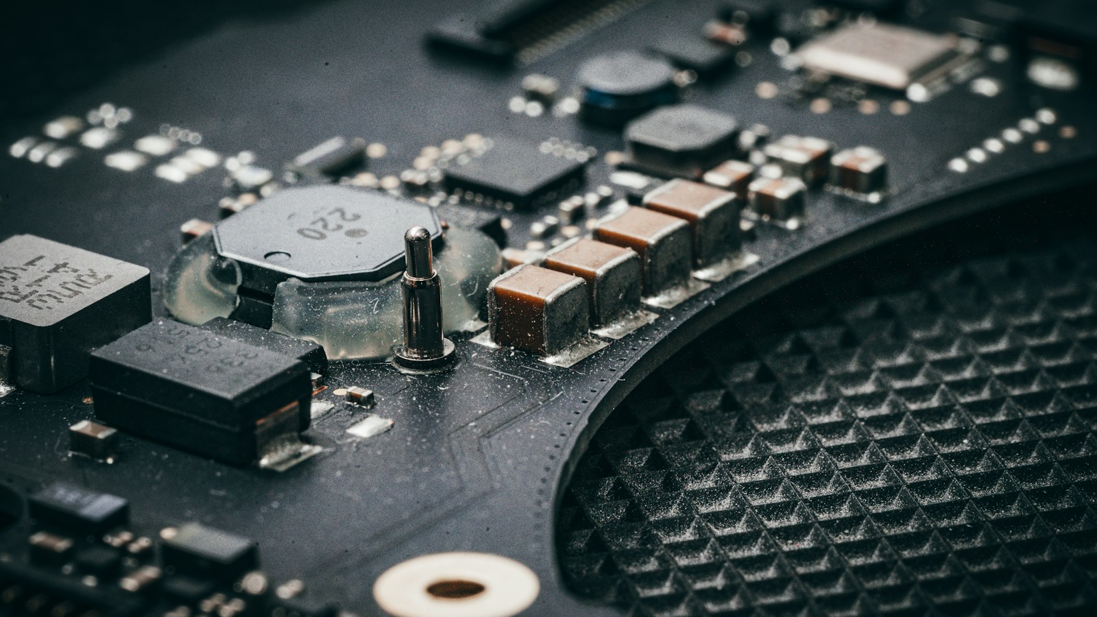 Close view of a circuit board containing processors, capacitors and other electronic components.