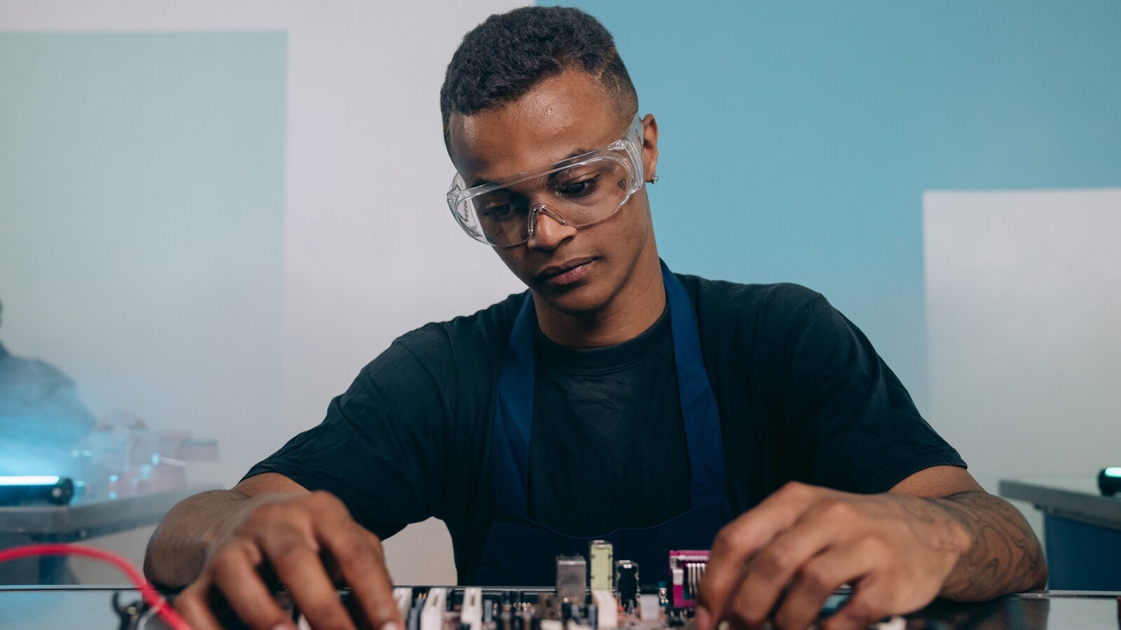 Electronics engineer assembling and inspecting a printed circuit board at a workbench.