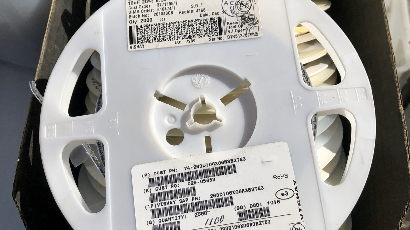 Reels of surface mount electronic components with manufacturer labels and part information.