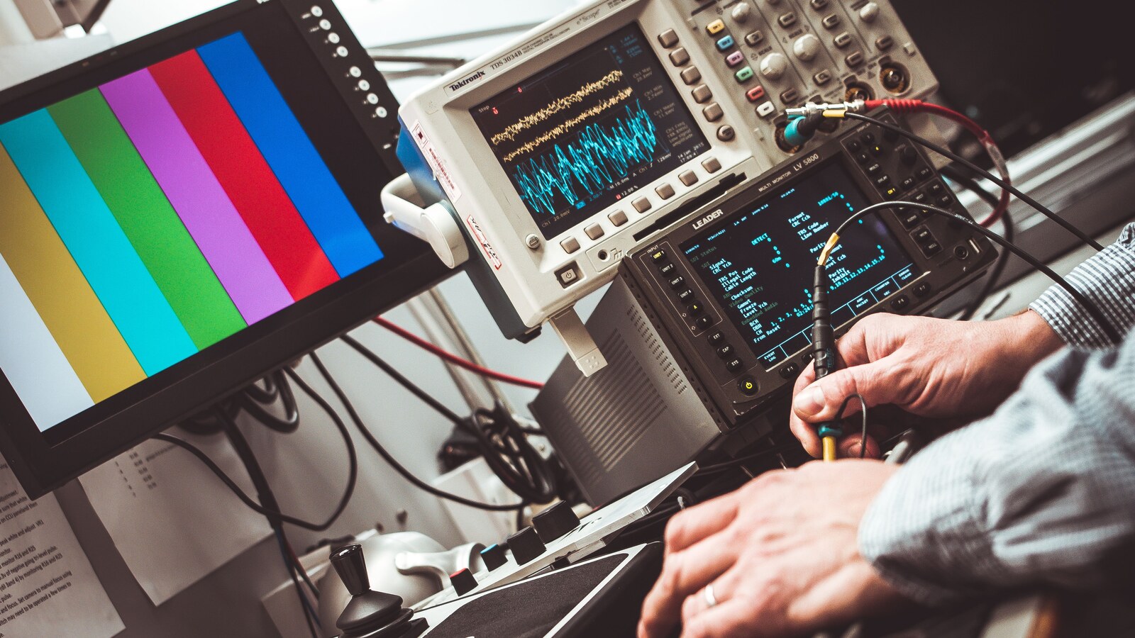 Engineer using an oscilloscope and other electronic test equipment on a laboratory bench.