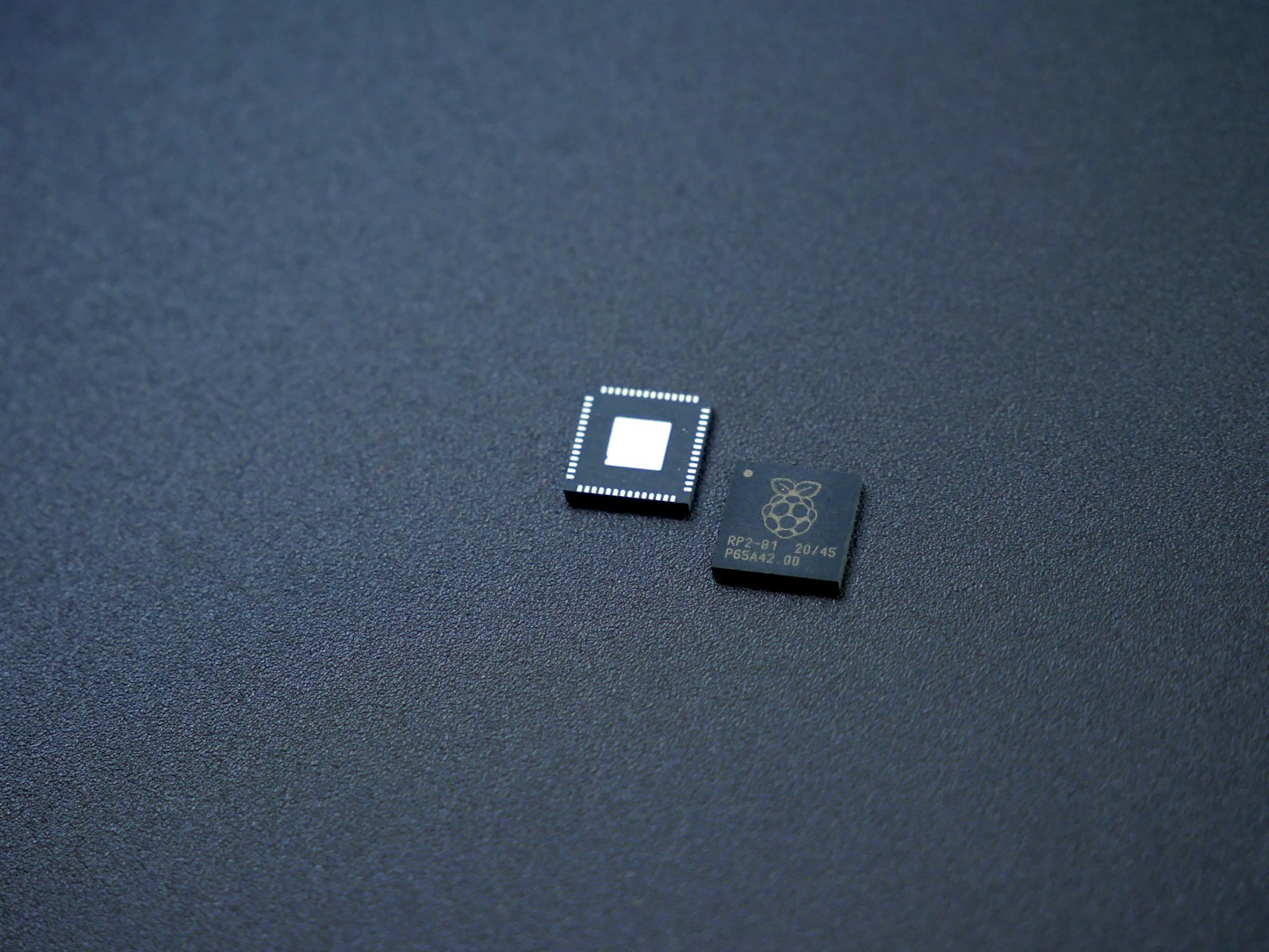 Two unmounted RP2040 microcontrollers shown as an illustration of packaged surface-mount components
