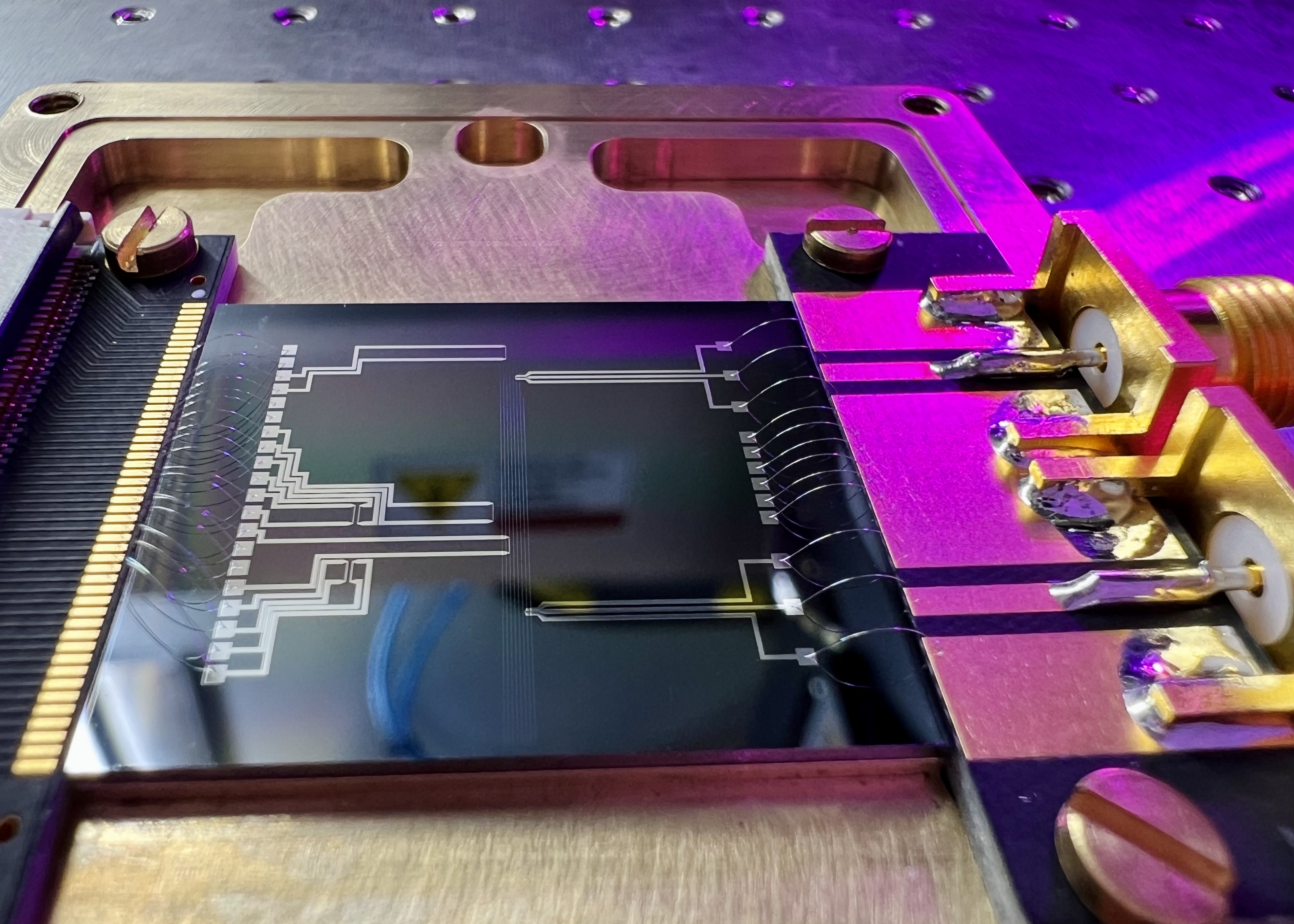 An electro-optical modulator chip fabricated by FMN Laboratory, shown during wire bonding. Illustrative archive image, not Cornell’s proposed computing hardware.