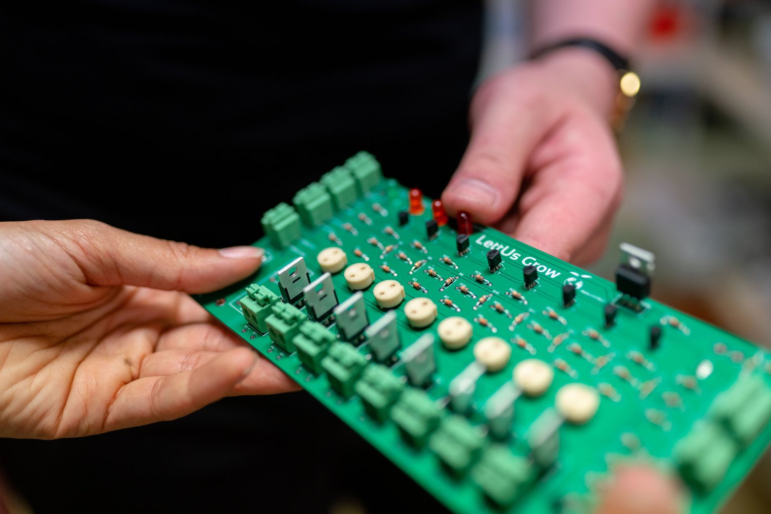 Hands holding a small green electronic circuit board