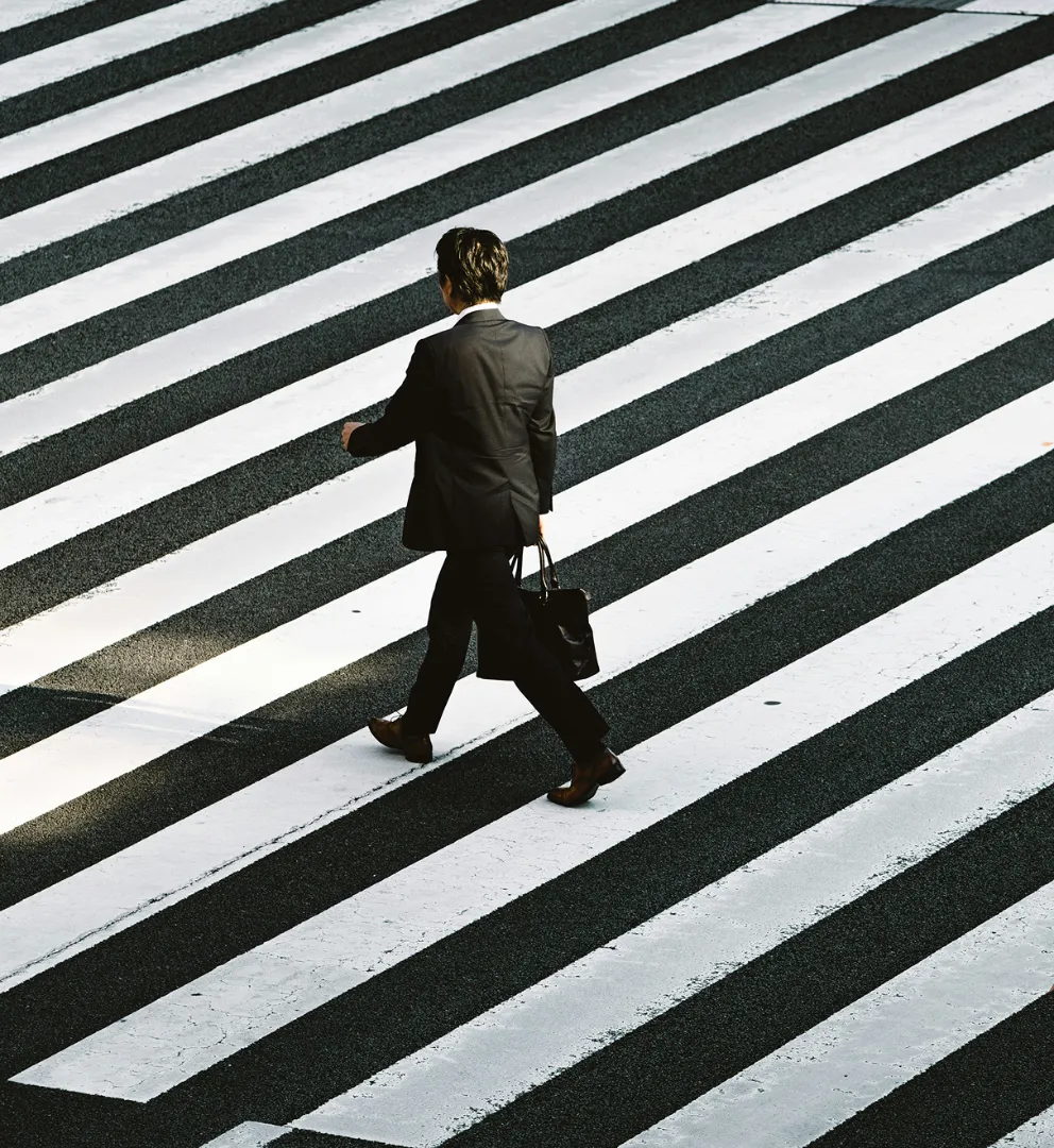 Businessman crossing a striped crosswalk, viewed from above