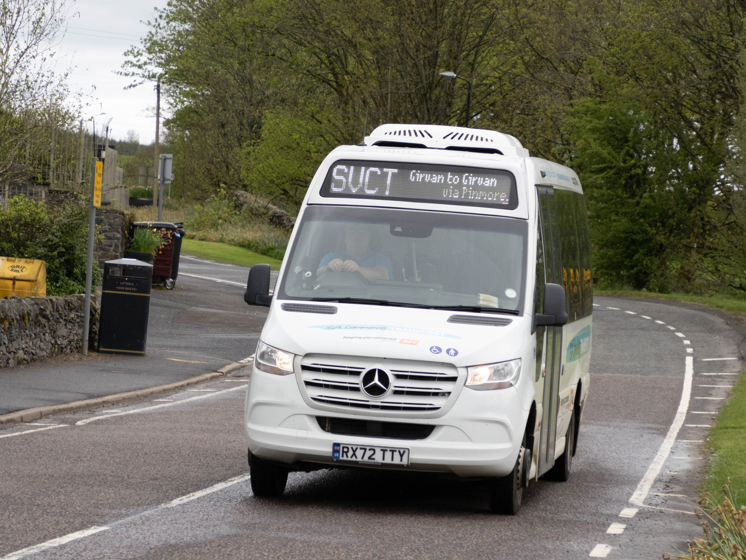 White Mercedes minibus on a rural road with route sign showing SVCT Girvan to Girvan via Pinmore.