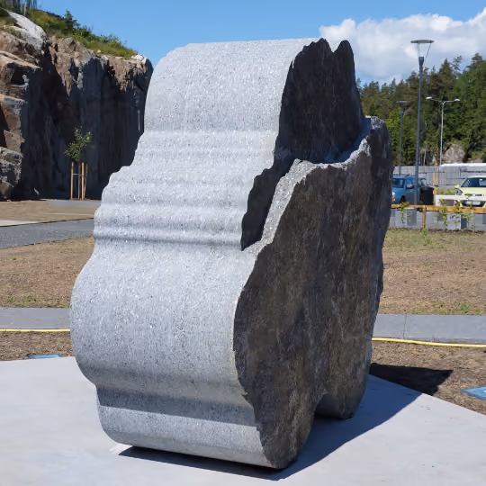 Utendørs skulptur laget av delvis polert og ubehandlet stein på en betongplattform.