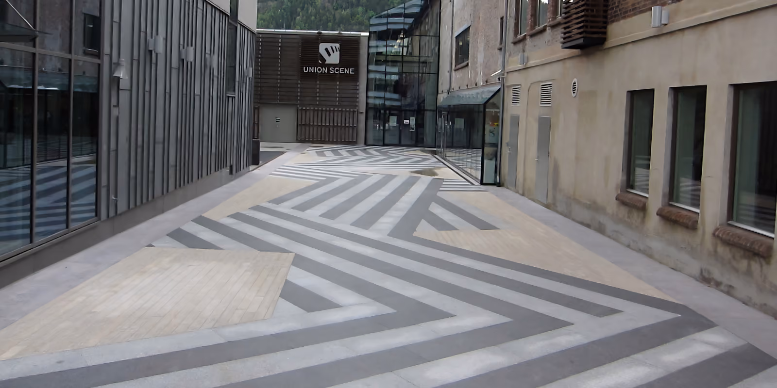 Glass and brick buildings with modern patterned pavement leading to Union Scene entrance.