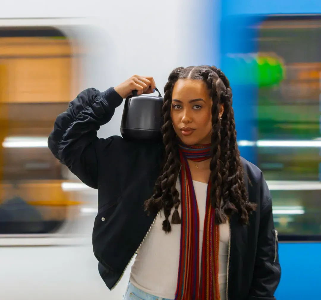 A podcaster carrying a Nomono Sound Capsule case on her shoulder through a subway station