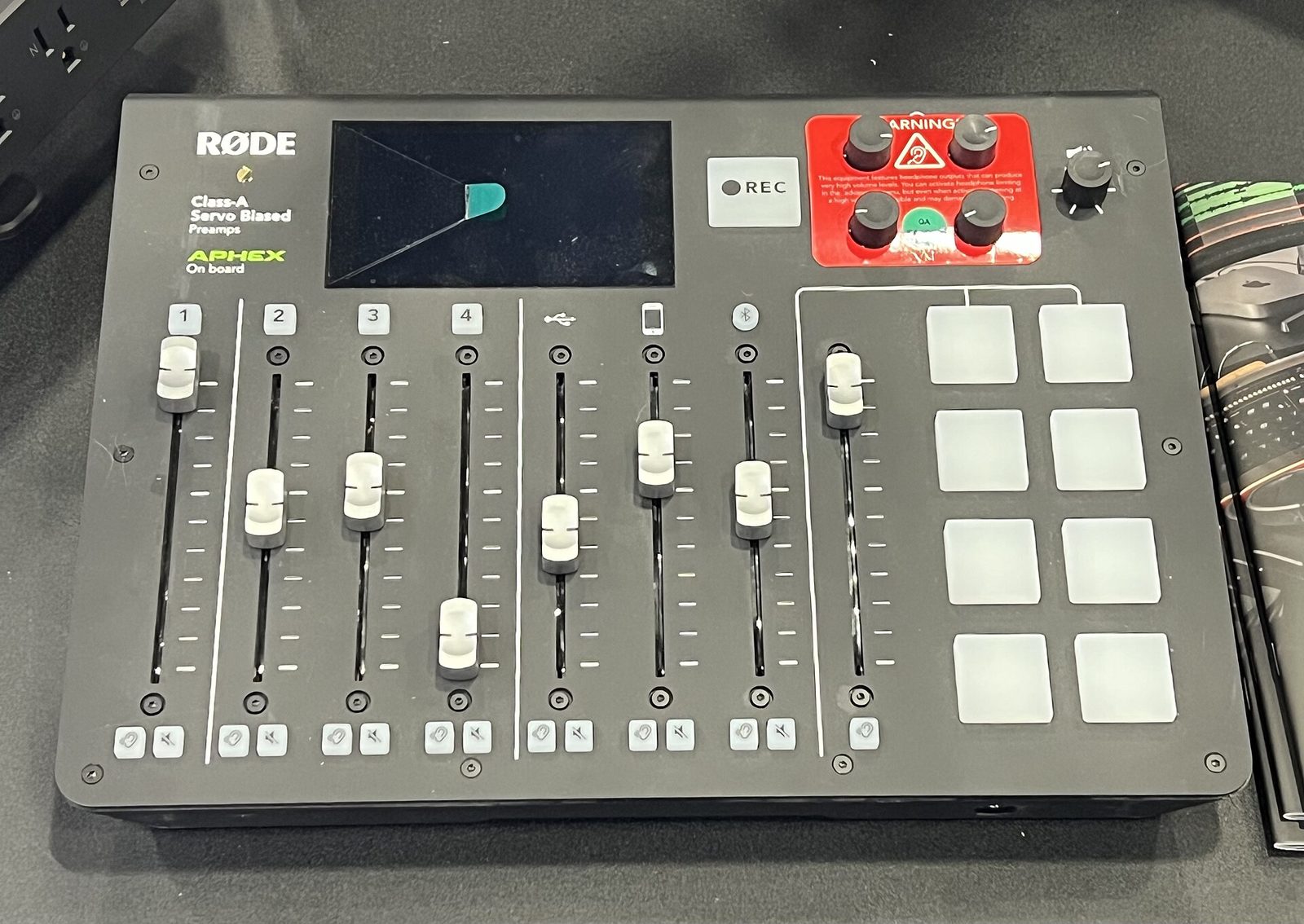 RØDE RØDECaster Pro podcast mixer, first generation, seen from above with four mic faders, USB, phone and Bluetooth channel faders, touchscreen and eight sound pads