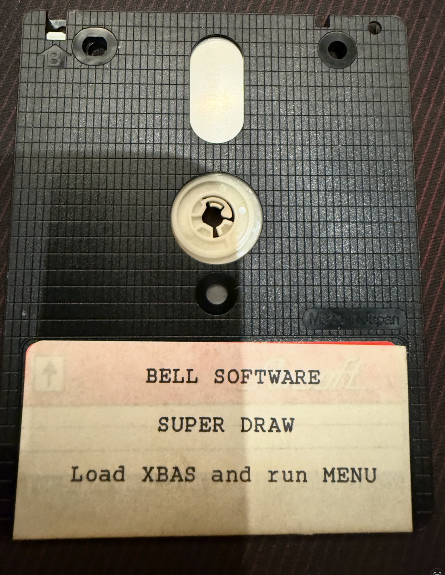 Side B of the disc: a typed label reading Bell Software, Super Draw, Load XBAS and run MENU, stuck over an Amsoft blank-disc label