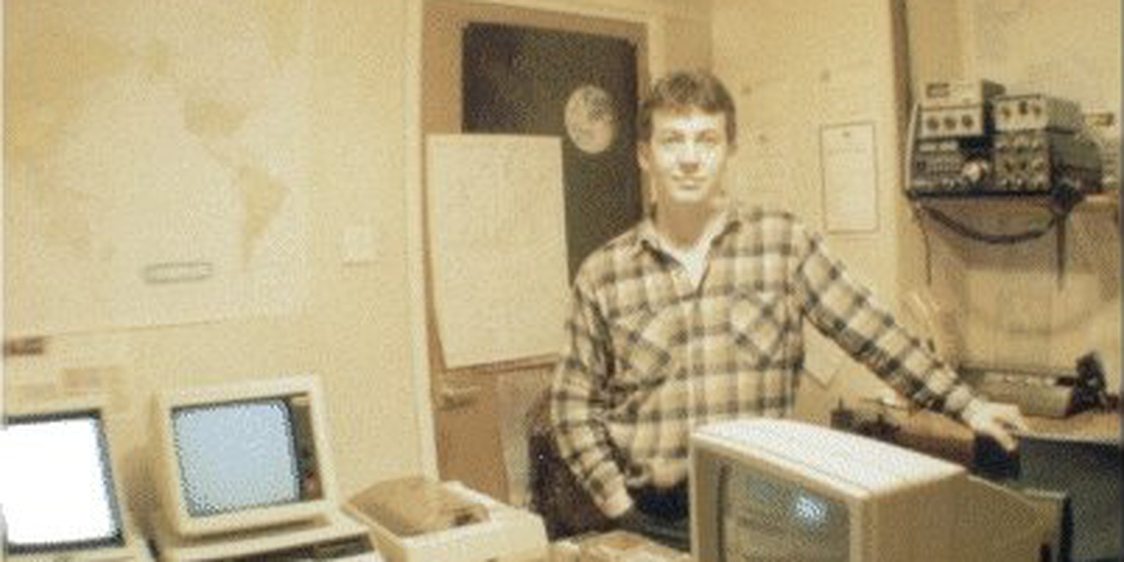 Pete Morris in his radio shack, radio equipment on the wall behind him and the computers on the desk in front