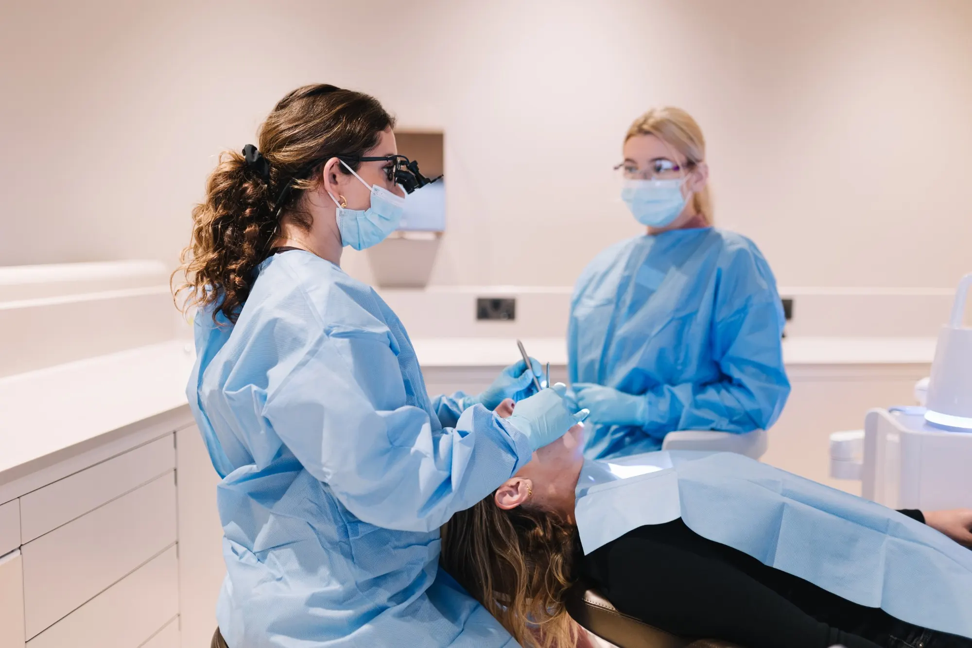 Dr Payvand Menhadji treating a patient with her assistant