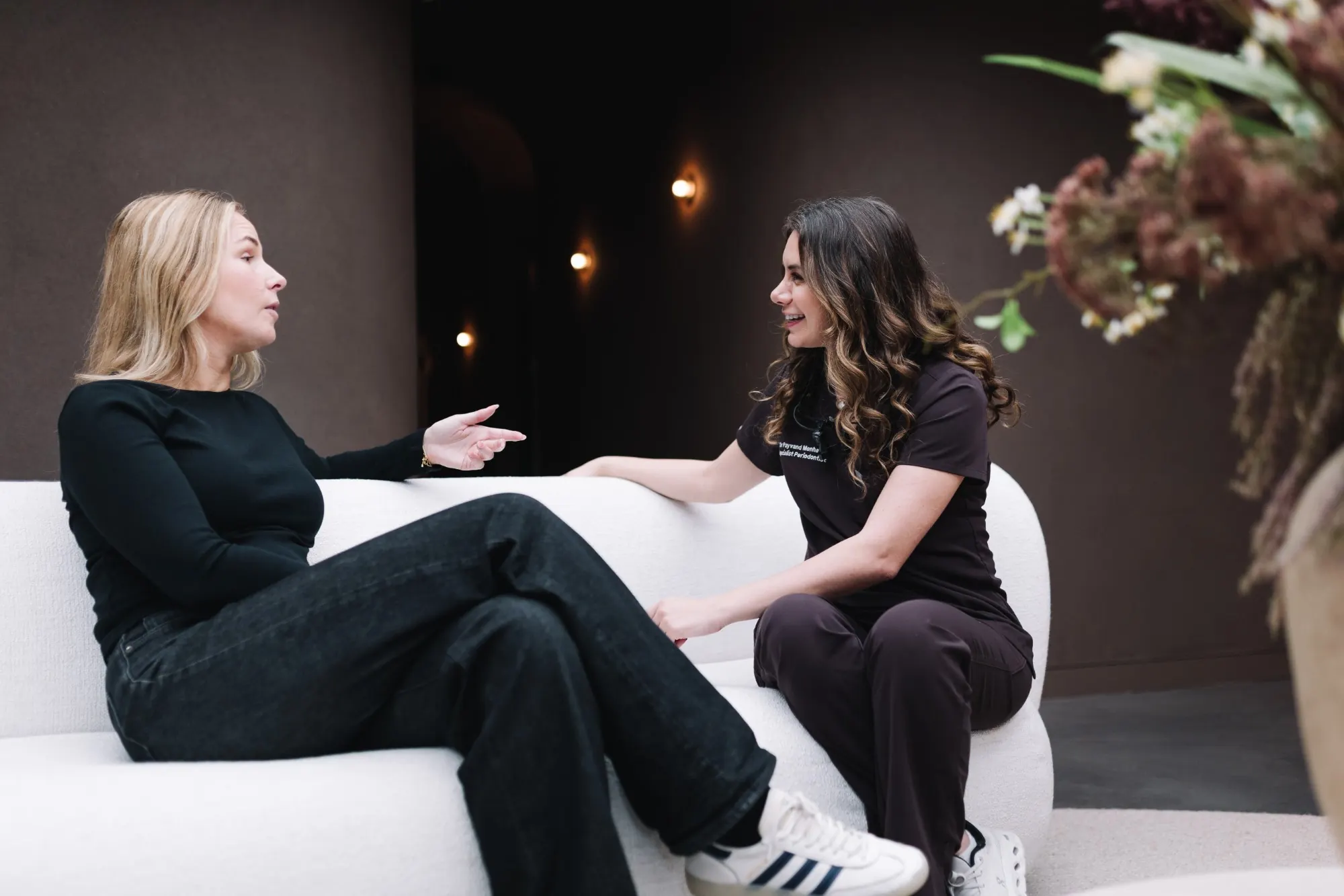 Dr Payvand Menhadji talking with a patient on a sofa