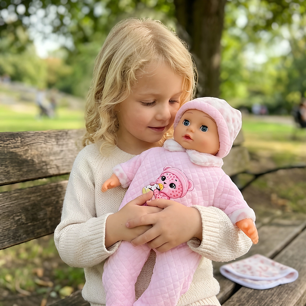 Blonde child in a cream sweater holding a doll dressed in pink on a park bench.