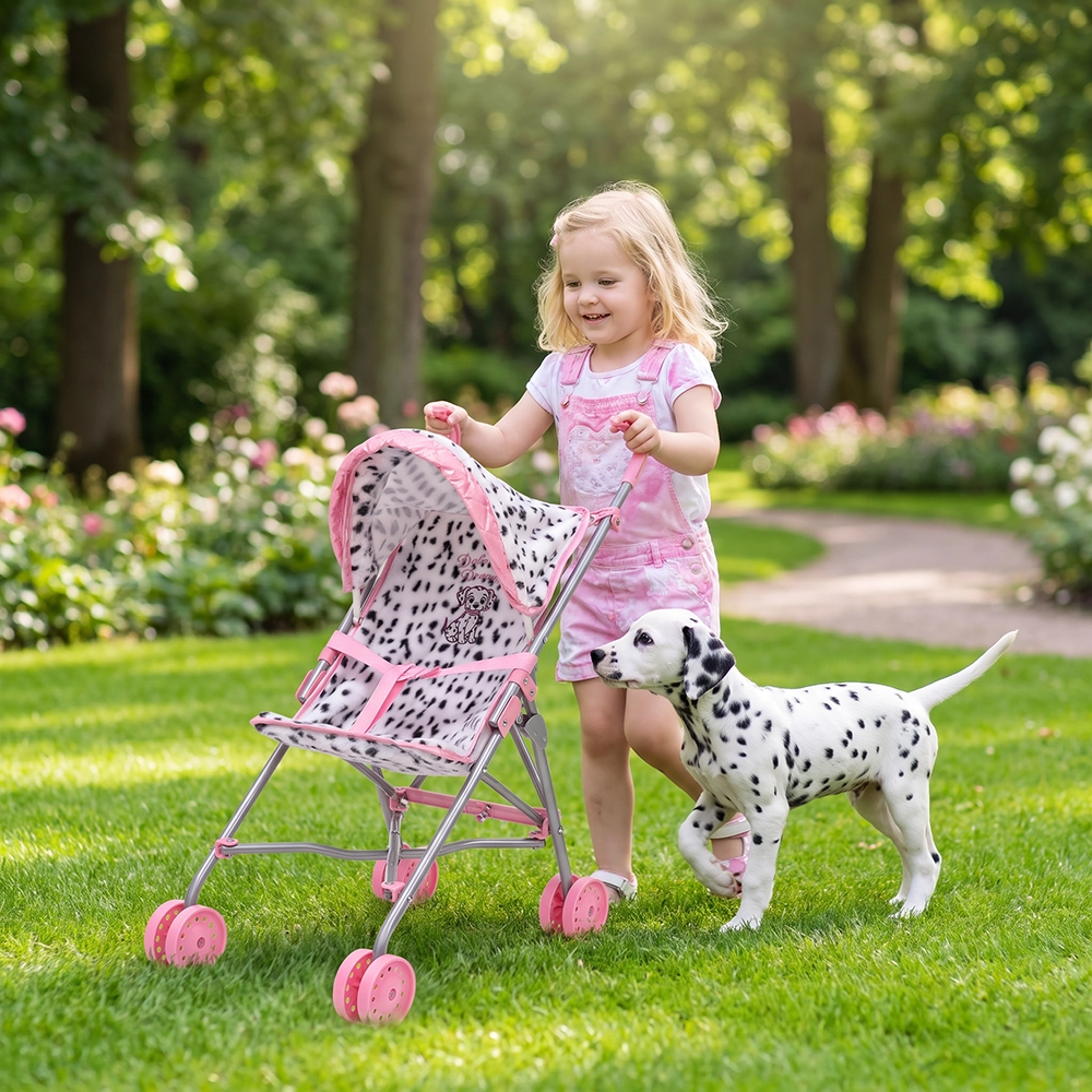 Little girl in pink pushing a pink-spotted toy stroller next to a Dalmatian puppy on grass.