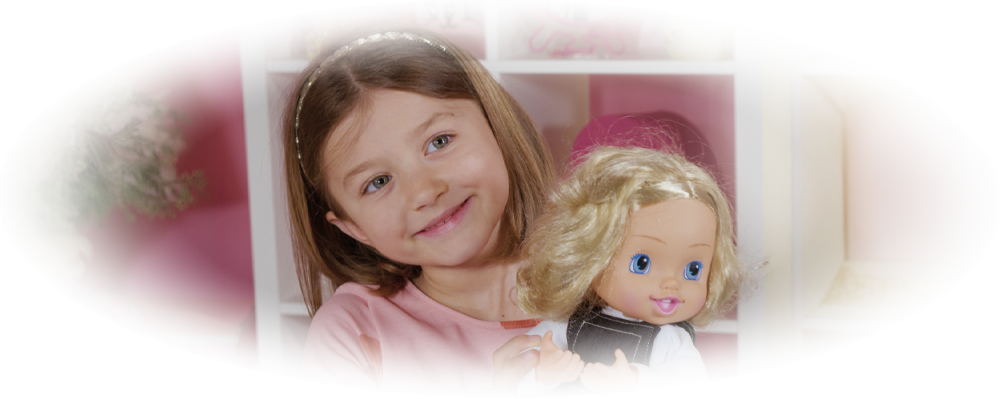 Smiling girl in pink shirt holding a blonde doll with blue eyes wearing striped pants.