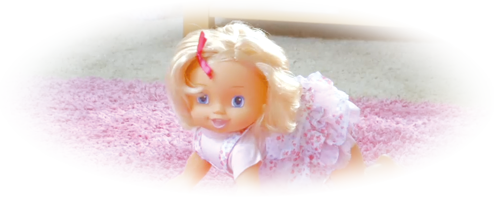 Blonde baby doll with a pink dress crawling on a pink carpet, child wearing blue shoes in background.