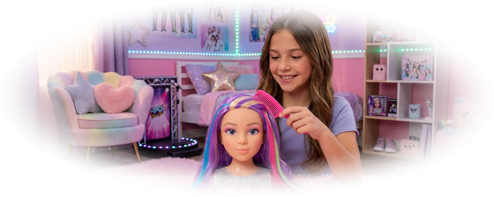 Girl combing a styling head doll with purple, pink, and blue hair in a colorful bedroom with K-POP posters.