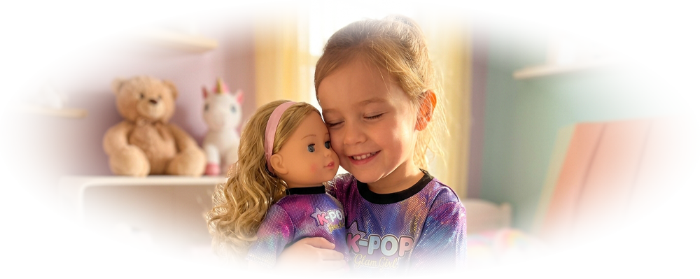 Smiling girl hugging a doll wearing matching K-POP Glam Girl outfits in a colorful bedroom.