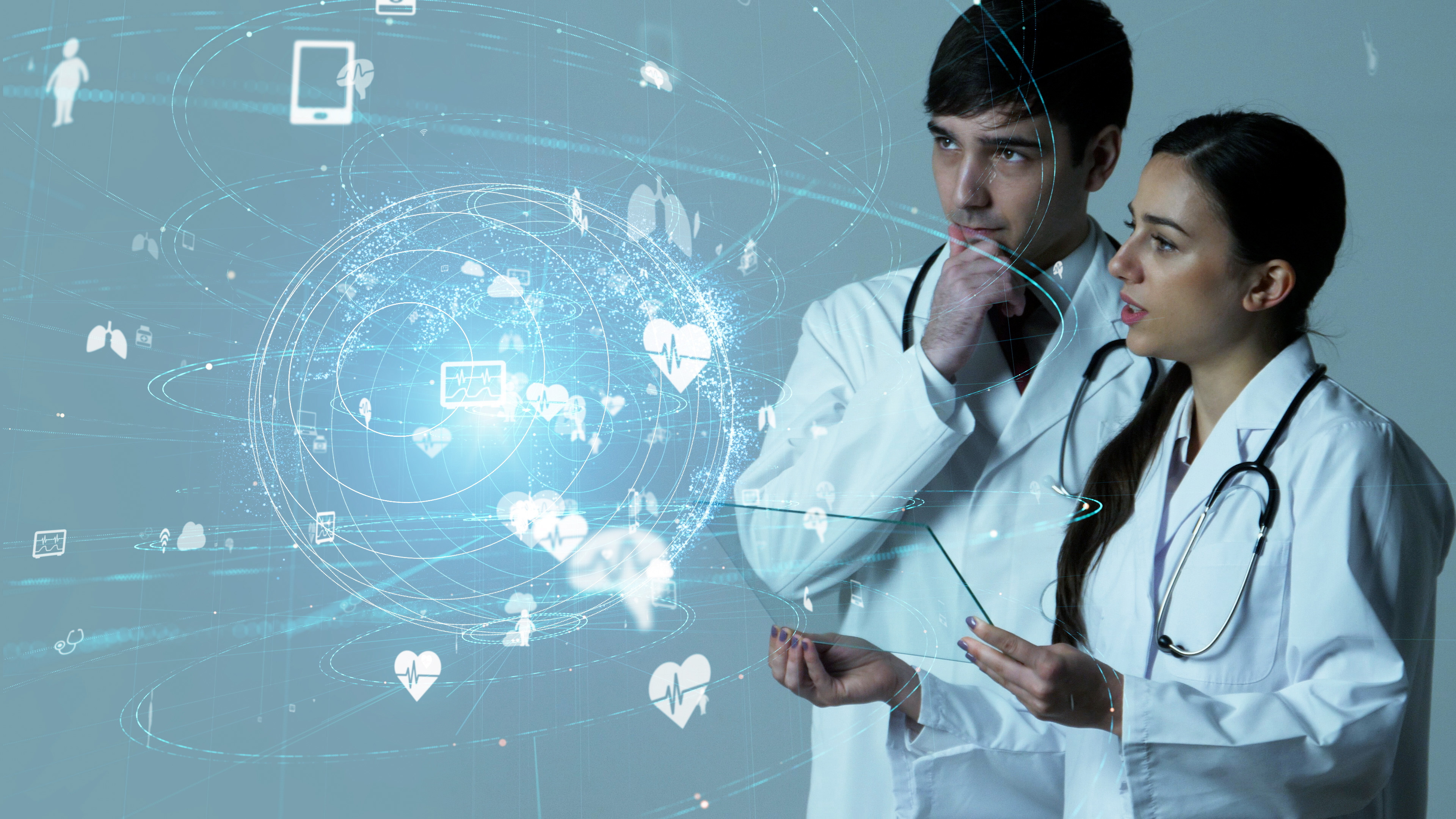 Two doctors in white coats with stethoscopes analyzing a futuristic digital health data display.