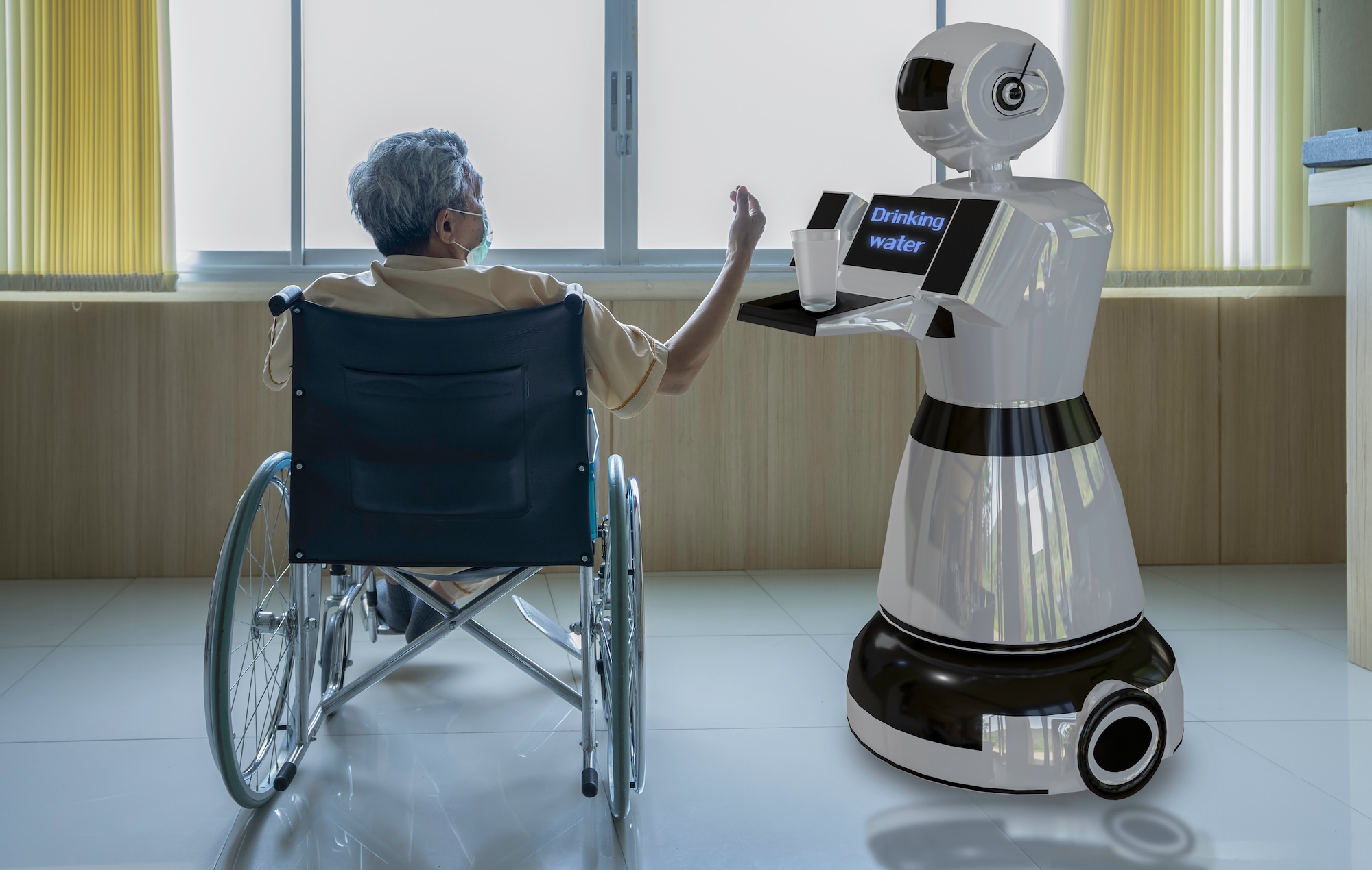 Robot serving a glass of water to a person in a wheelchair wearing a mask in a room.