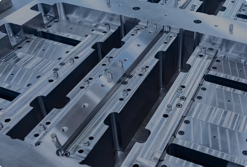 Close-up view of a polished metal mold with detailed cavities and pins used for industrial manufacturing processes.