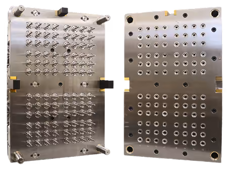 Two large metallic precision mold plates with multiple evenly spaced nozzles and holes facing each other, used for industrial injection molding or production processes.