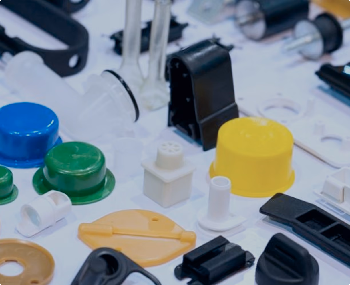Assorted small plastic parts and components in various colors, including blue, green, yellow, white, and black, arranged on a white surface.