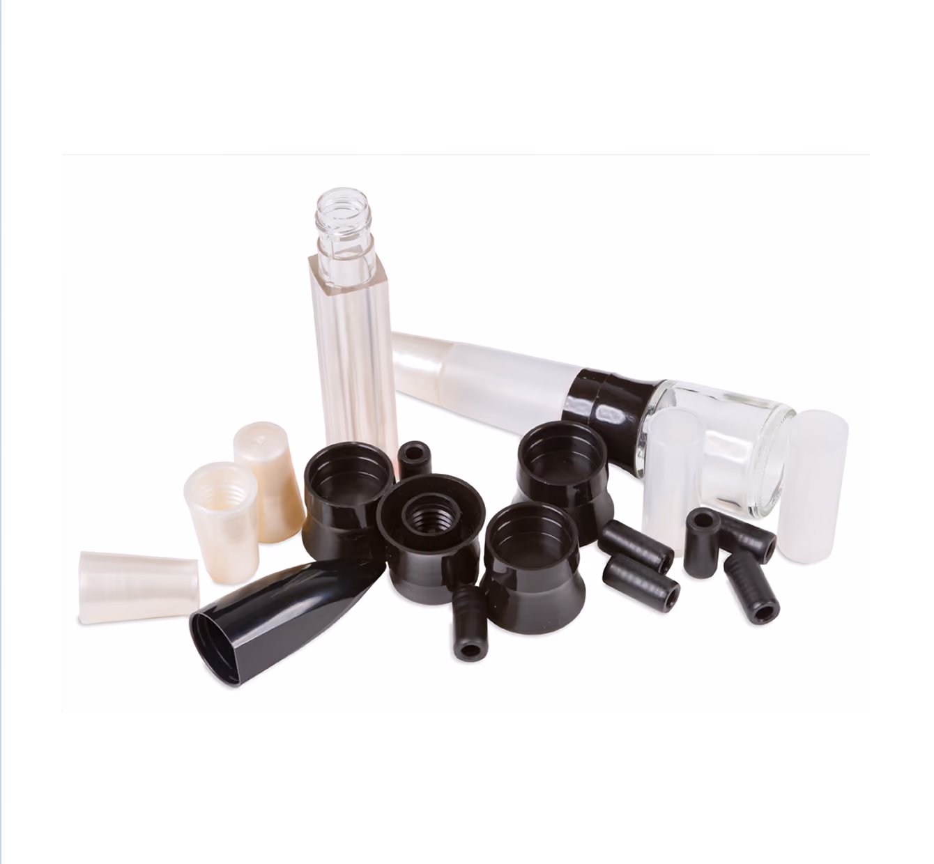 Various cosmetic packaging components including clear lip gloss tubes, black plastic caps, and small black plastic connectors arranged on a white background.