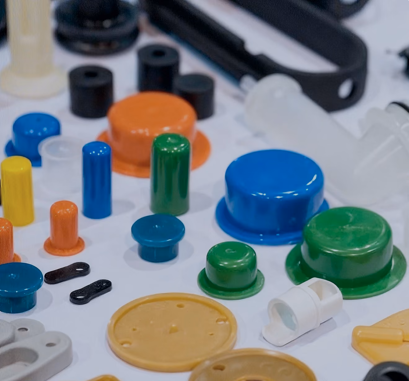 Various colorful plastic caps and small parts arranged on a white surface, including blue, green, orange, yellow, and black pieces of different shapes and sizes.
