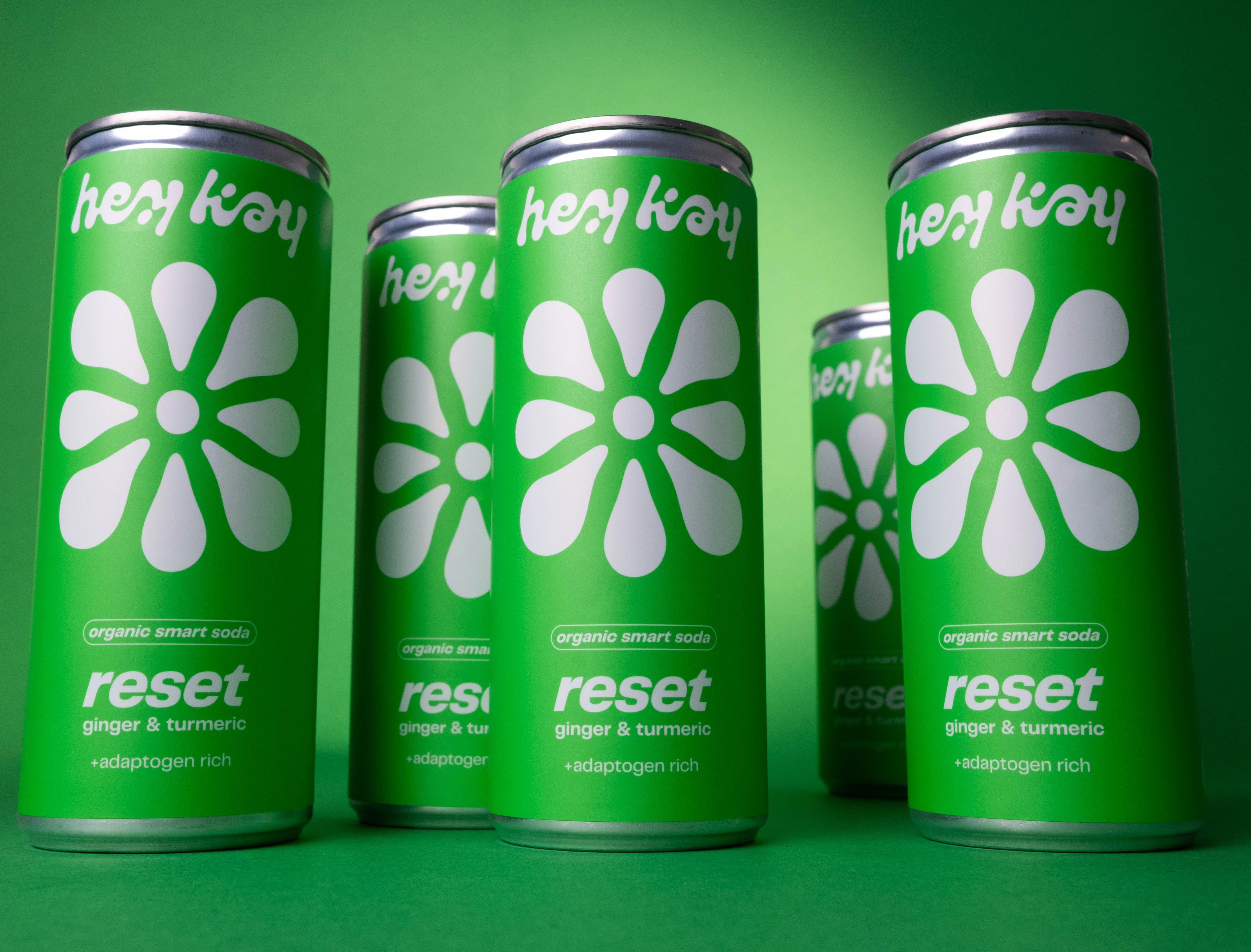 Latas de hey kay reset, refrigerante com gengibre e curcuma, em fundo verde