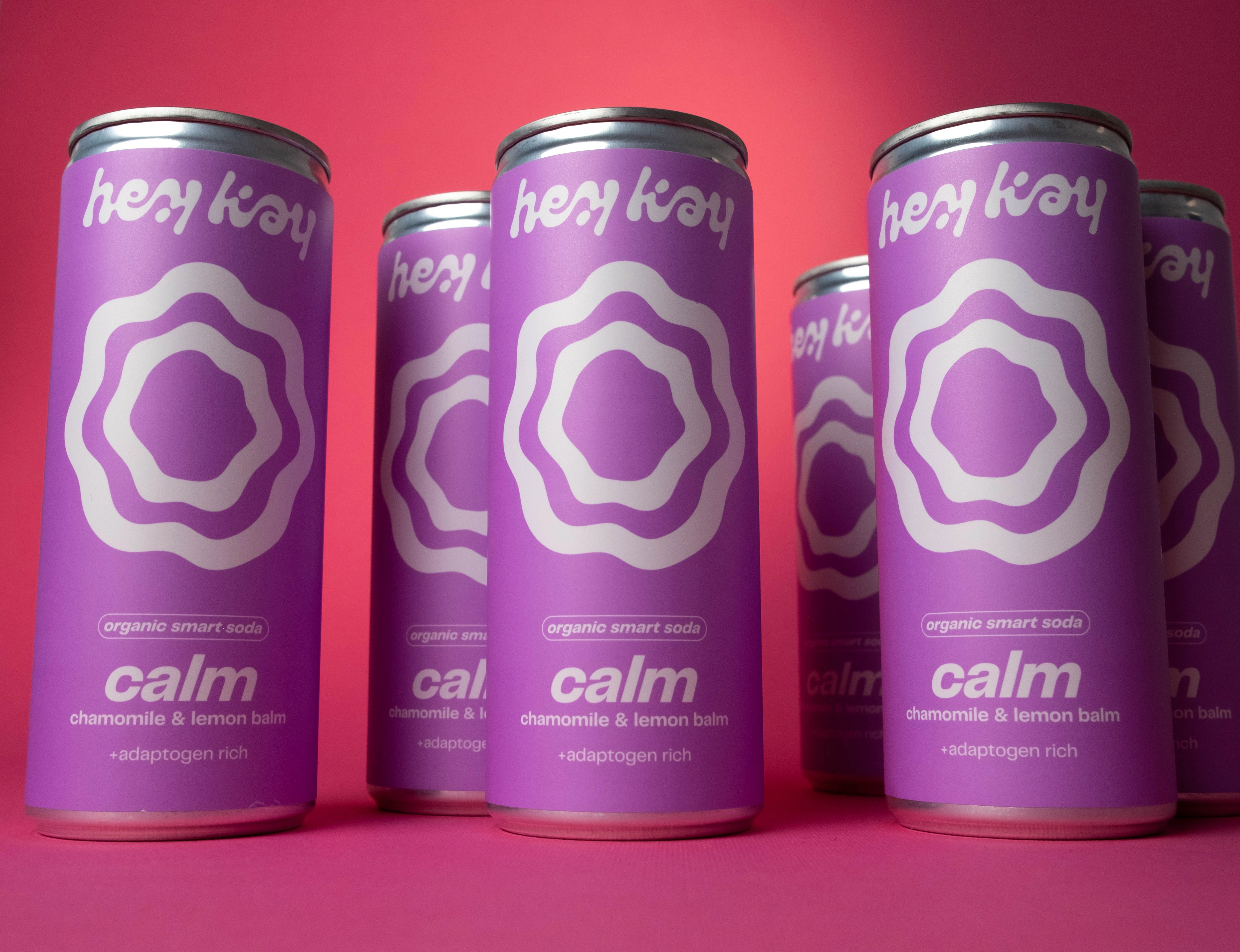 Latas de hey kay calm, refrigerante com camomila e erva-cidreira, em fundo rosa