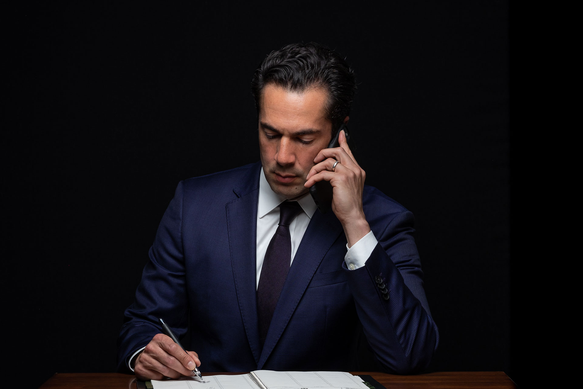 Marco Crawford, professional attorney lawyer reviewing legal documents while on phone call