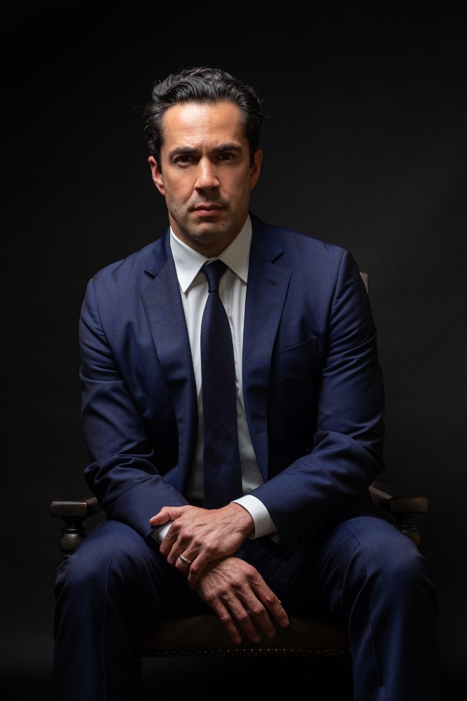 Professional portrait of attorney Marco Crawford, experienced lawyer in formal blue suit and tie.