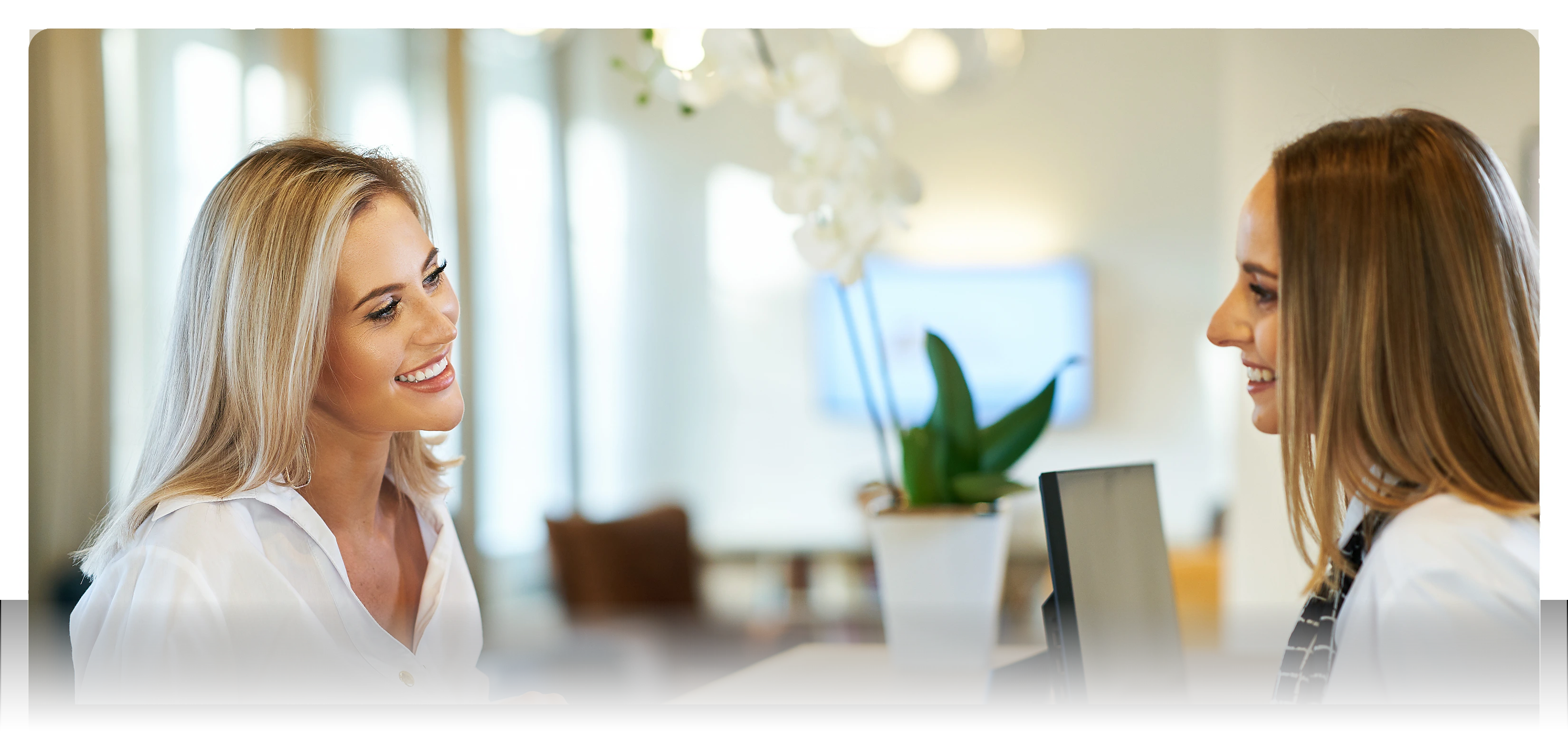 Smiling female healthcare professional showing a tablet to a male patient in a bright medical office.