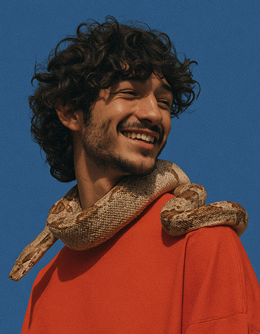 Portrait of a smiling man with a snake wrapped around his neck